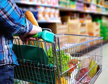 Consumer pushing shopping cart in supermarket.