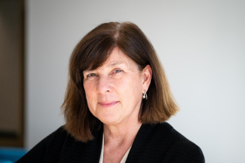 Smiling woman with brown hair wearing black against white background
