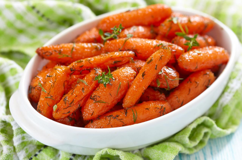 Roasted carrots in a white dish on a green kitchen towel