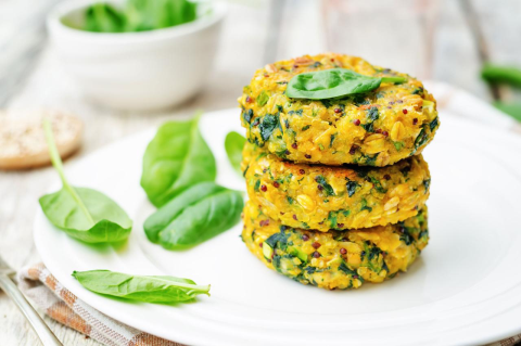 Three stacked quinoa and chickpea burgers on a white plate