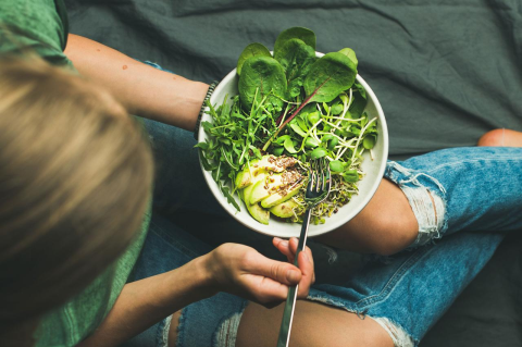 A vegan bowl of spinach, avocado, sprouts, and other vegetables.